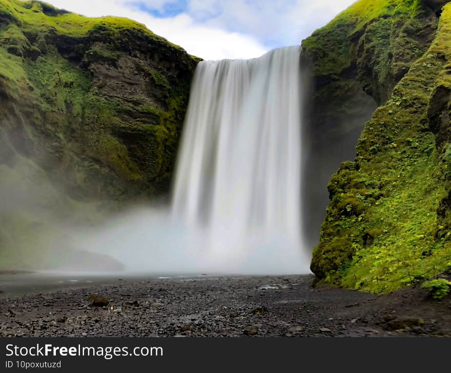 Skogafoss Waterfall with long exposure under a cloudy sky in Iceland