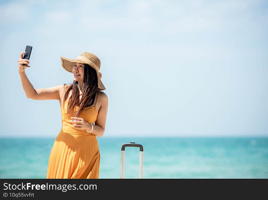 Summer vacations. Lifestyle woman selfie and relax chill on beach background.  Asia happy young people wearing yellow dress fashion summer trips walking enjoy  tropical beach. Lifestyle and Travel Concept