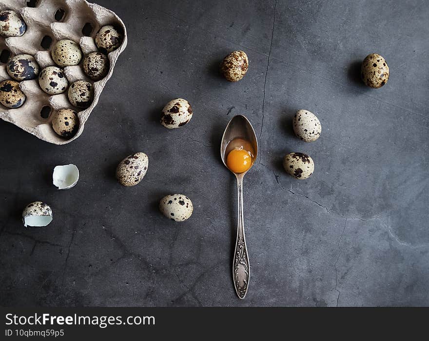 Composition of quail eggs in eco-friendly packaging with a spoon with the yolk. The view from the top