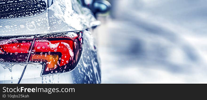 Manual car wash with white soap, foam on the body. Washing Car Using High Pressure Water.