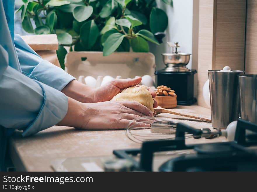 Girl kneading dough in the kitchen, close-up. A woman at home prepares dough for delicious pastries or cookies. Culinary background