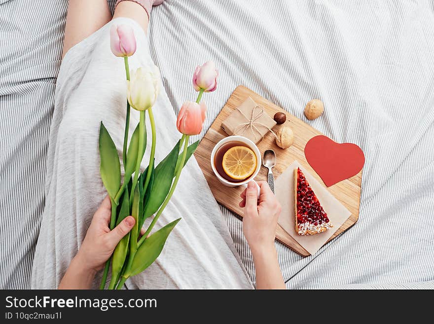 Surprise in bed. Breakfast, flowers and a gift for a girl on Valentine`s Day. congratulations for February 14