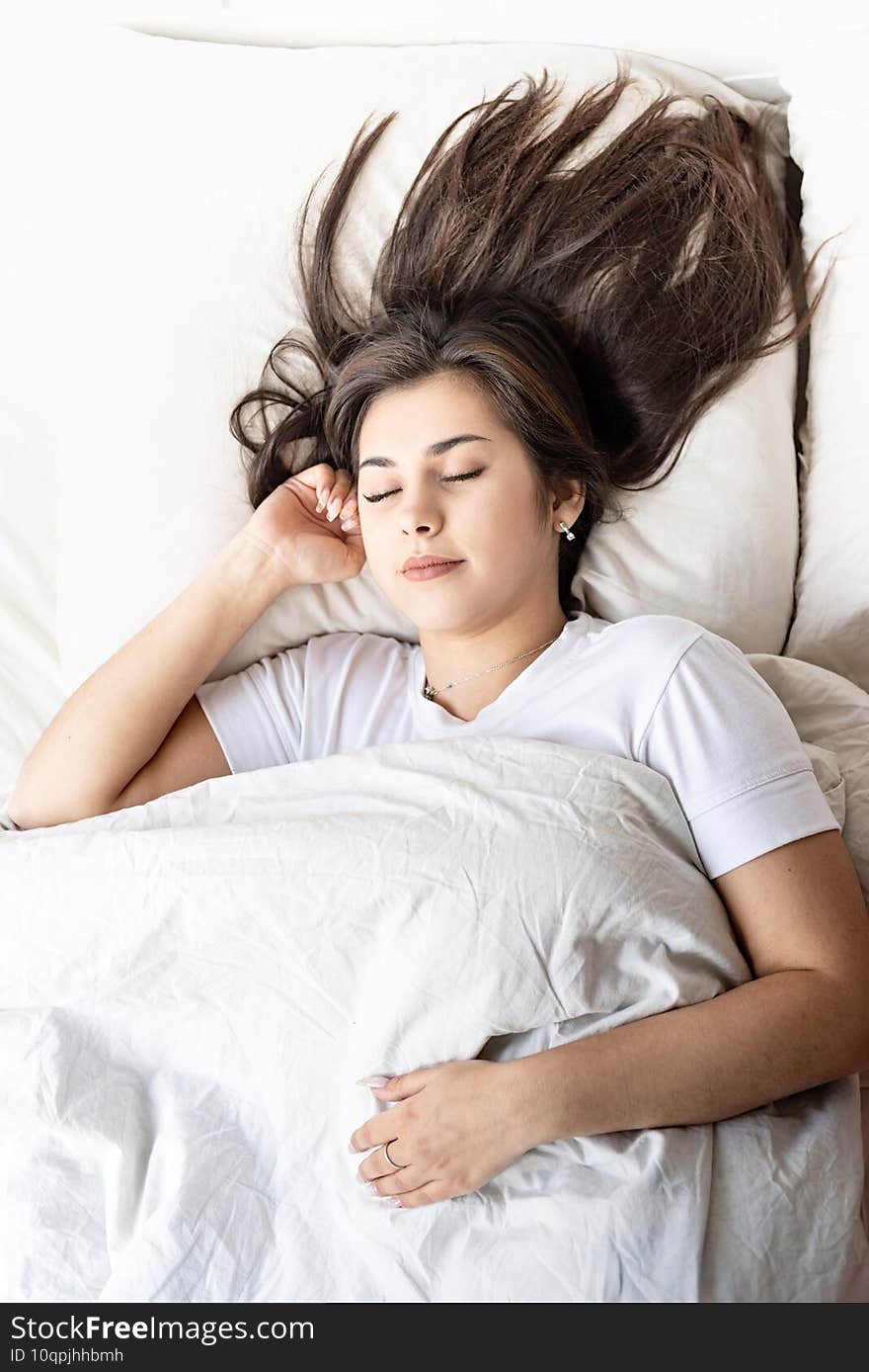 Young beautiful brunette woman sleeping in bed