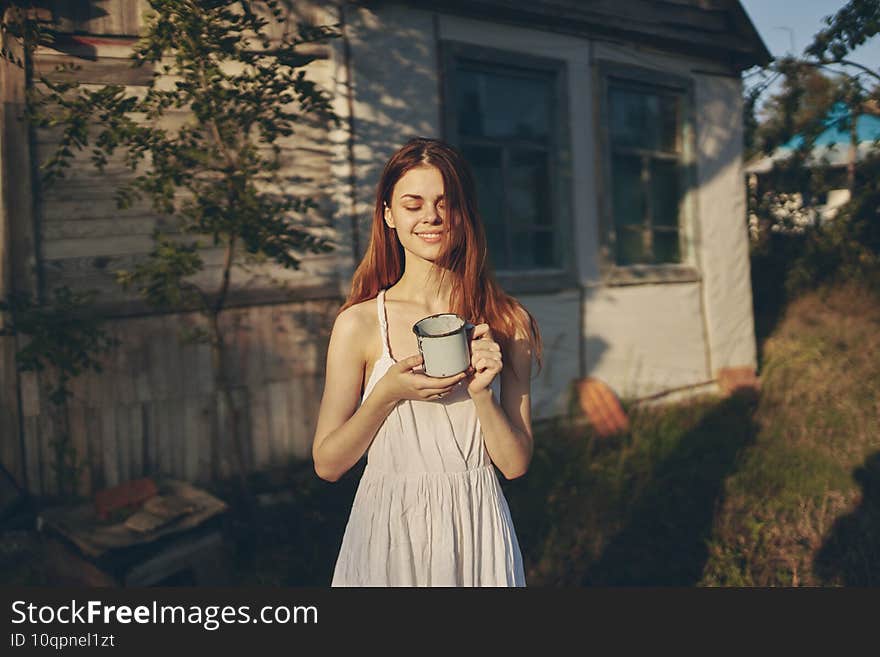 happy woman near building with iron mug outdoors in garden