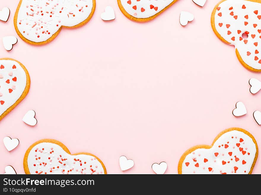 Homemade cookies for valentine\'s day sprinkled with hearts on a pink background with copy space