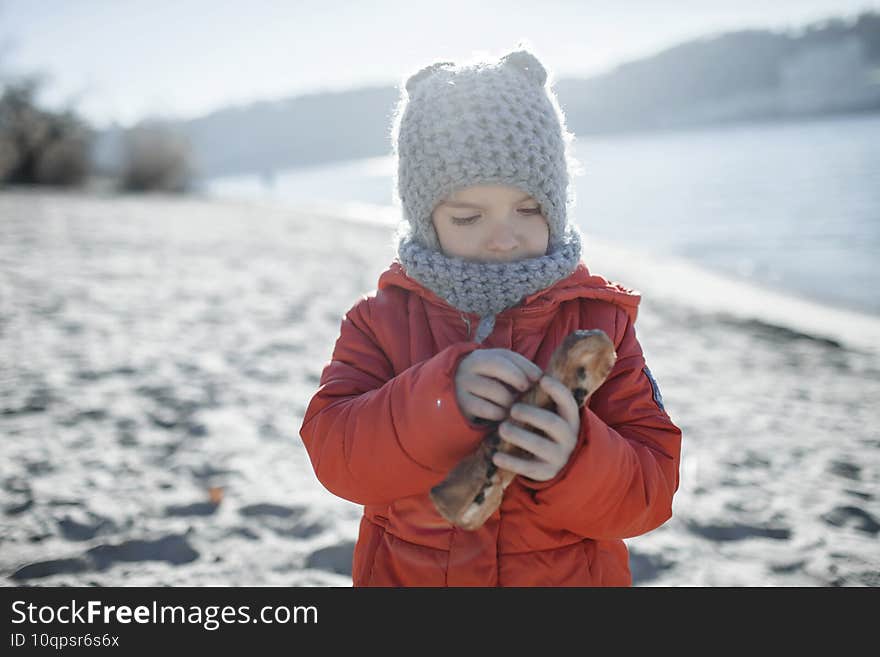 Kid walking at the beach in winter, cold temperature and sunny day, love keep you warm