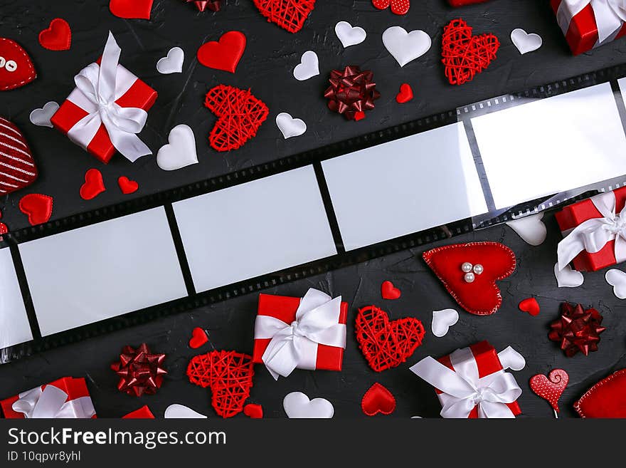 Film form frame with hearts and gifts on black background. Space for text or image. Top view Valentine`s day composition