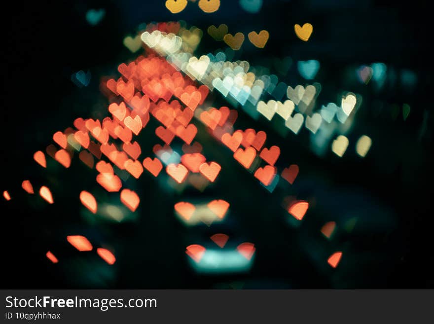 Abstract heart-shaped bokeh from cars in film look.