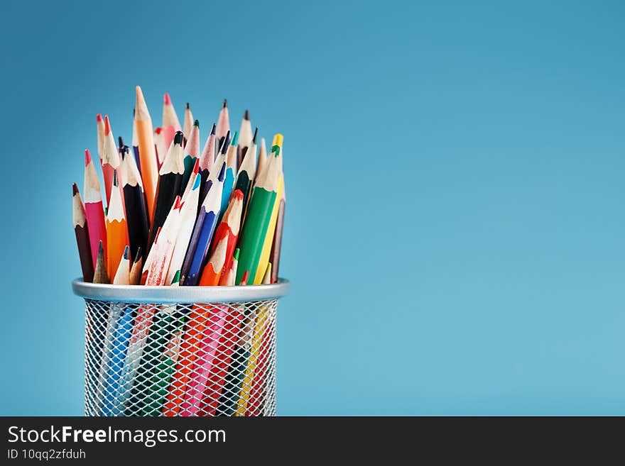 Colorful pencils in a metal jar on a blue background