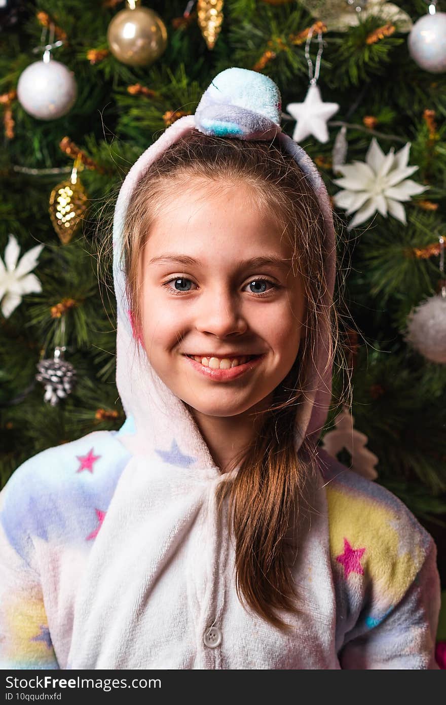 Little girl in home costume with hood with Christmas background.