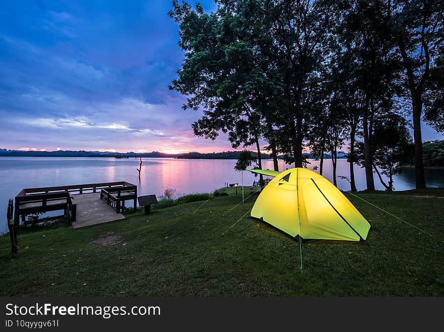 Camping tent on green grass field under cloudy sky