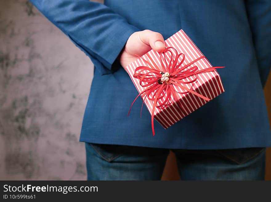 close up of man hands holding gift box behind his back