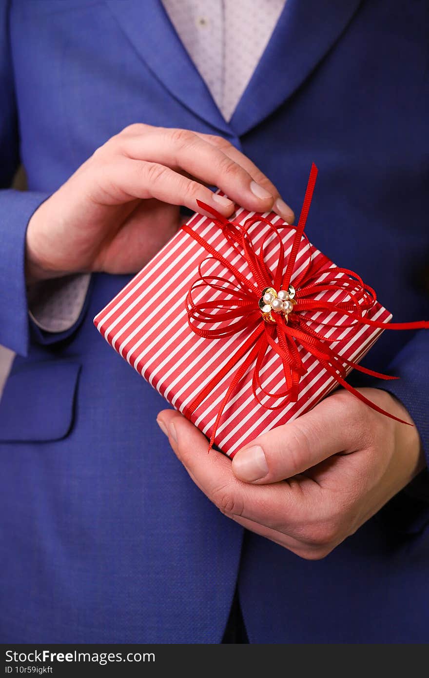 man in suit holds gift box.