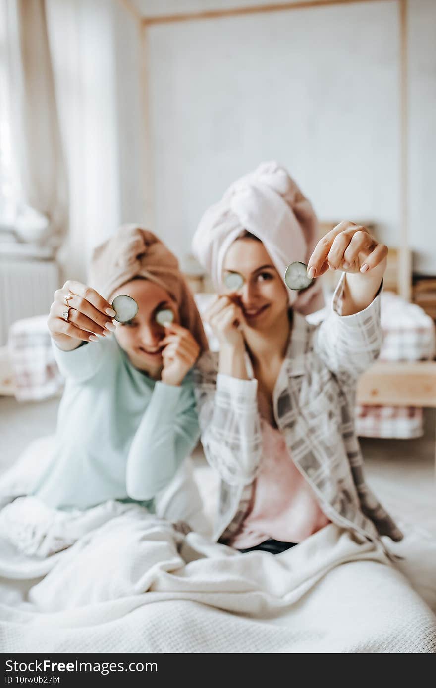 Two girls make homemade face and hair beauty masks. Cucumbers for the freshness of the skin around the eyes. Women take care of youthful skin.