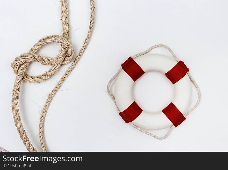 Flat lay with sea rope knot and lifebuoy on white background