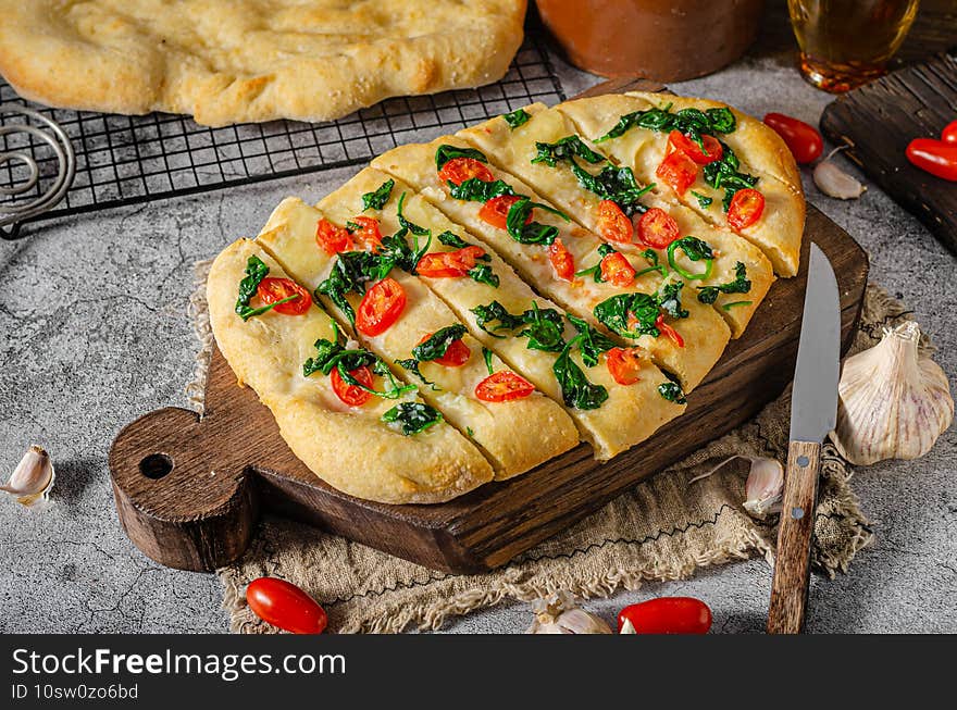 Delicious foccaccia with baby spinach,garlic and cherry tomatoes. Delicious foccaccia with baby spinach,garlic and cherry tomatoes