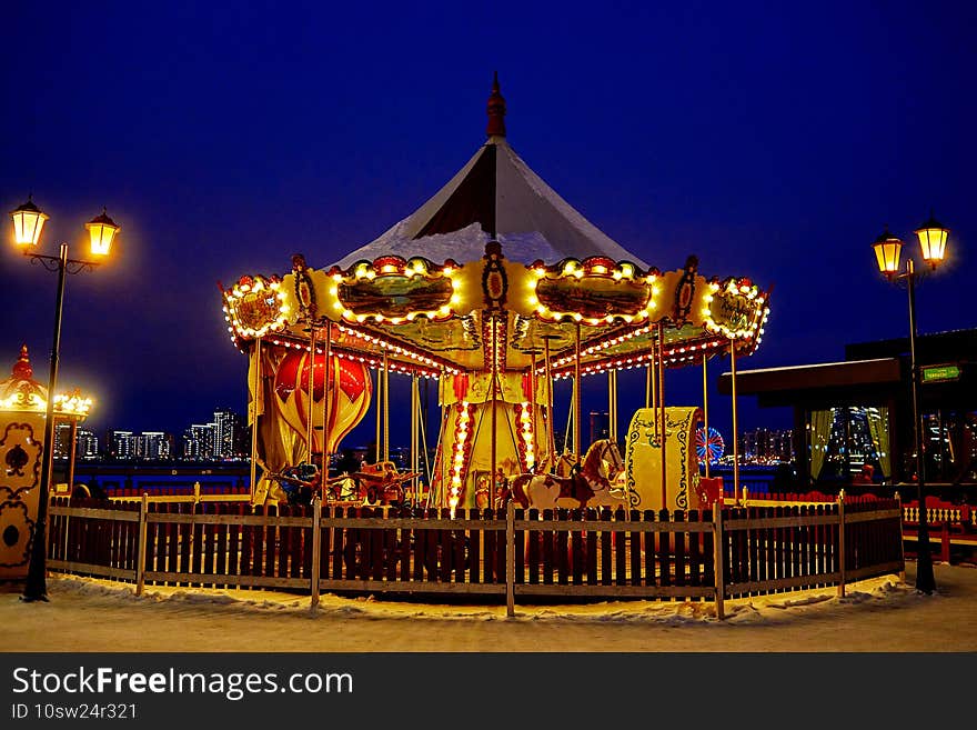 the carousel is illuminated by lights and lanterns. evening cityscape