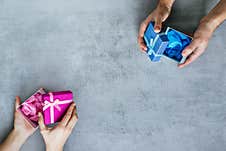 Protection From Covid-19. Male And Female Hands Hold Pink And Blue Gift Boxes With Gloves Inside On The Copy Space Stock Photo