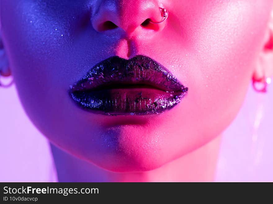 Close up view of beautiful woman lips in colourful bright neon uv lights.