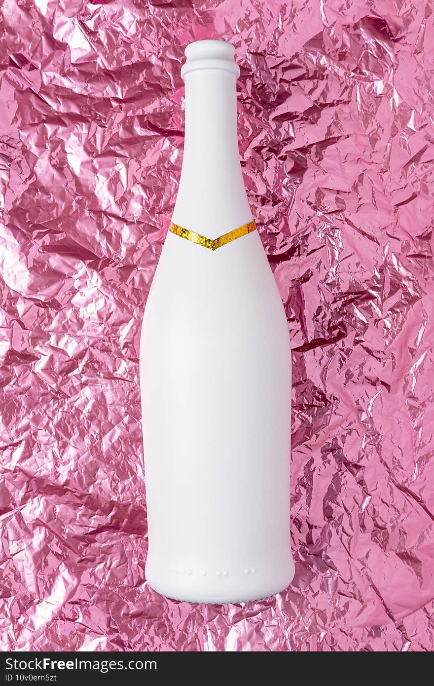 White champagne bottle on pink crumpled foil background. Minimal party concept