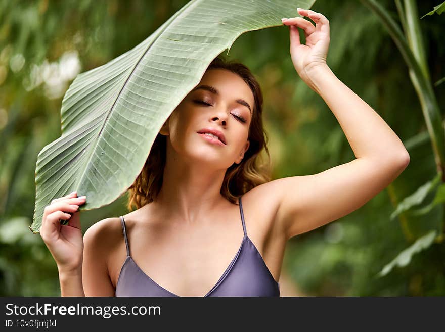 affectionate woman in summer garden holding plant leaf in hands, enjoys being close to nature. affectionate woman in summer garden holding plant leaf in hands, enjoys being close to nature