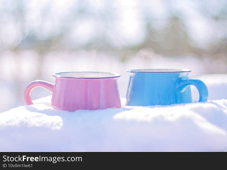 Two cups stand in the snow on a winter sunny day