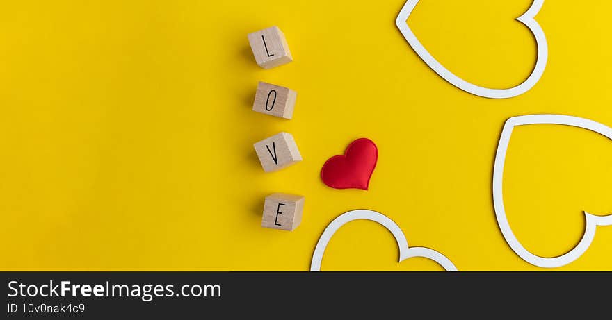 Three hearts made of white cardboard and letters with the word love on a yellow background with space for text. Postcard layout