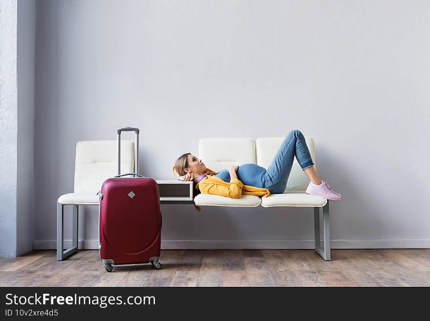 Pregnant woman lying on chairs near suitcase in hall of airport. Pregnant woman lying on chairs near suitcase in hall of airport