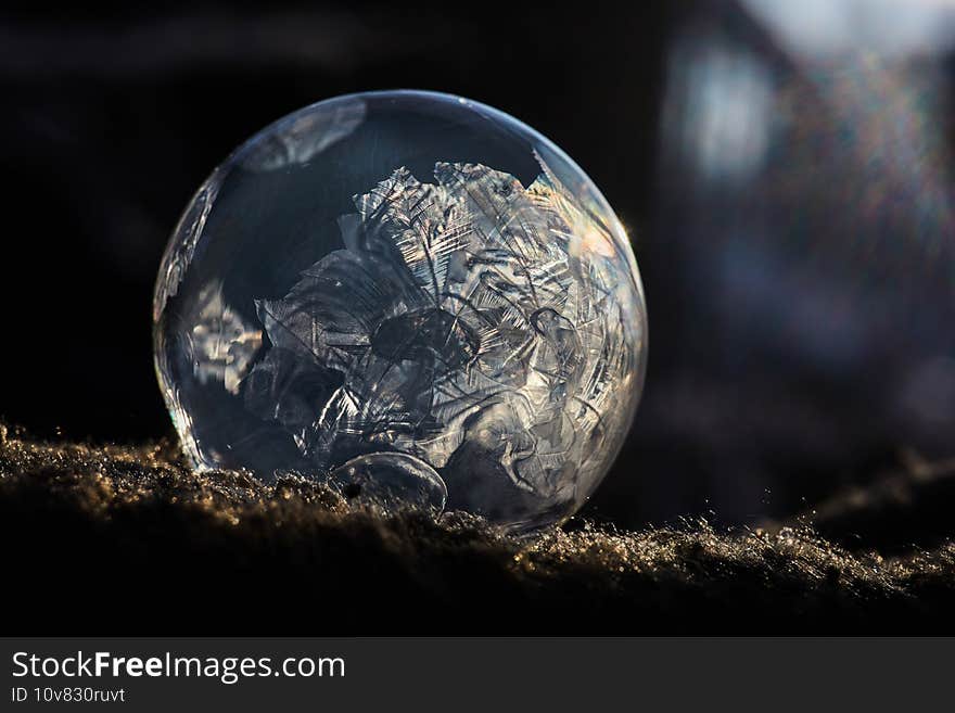 Frozen soap bubble with ice crystals at sunlight