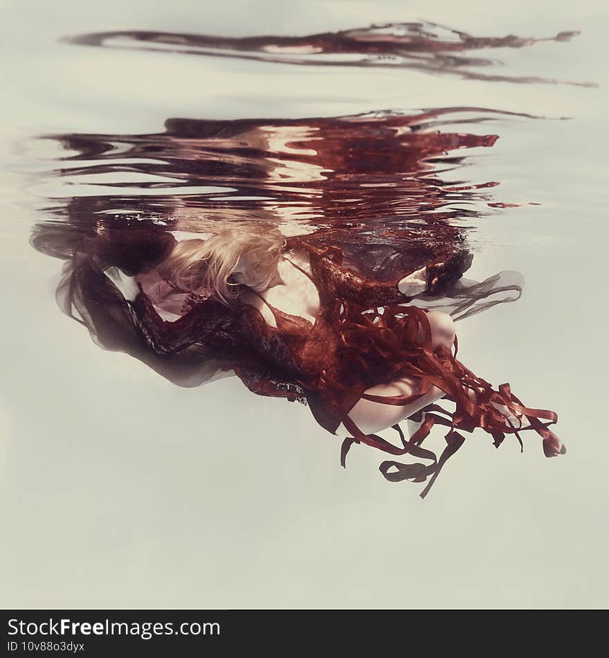 Woman in red dress swims underwater