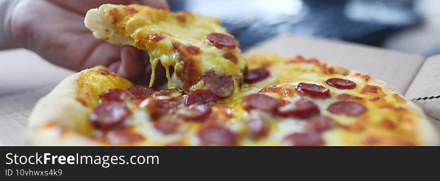 Man takes pizza slice with sausage close-up