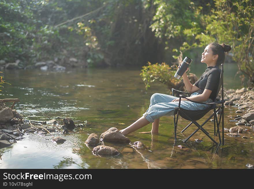 A beautiful young traveler woman is enjoying with nature drinking coffee in the morning over lake, relaxation , camping holiday and travel concept