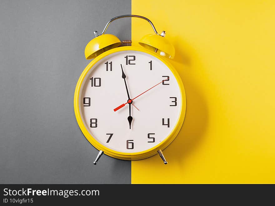 Illuminating color Retro style alarm clock on ultimate gray and yellow background, front view