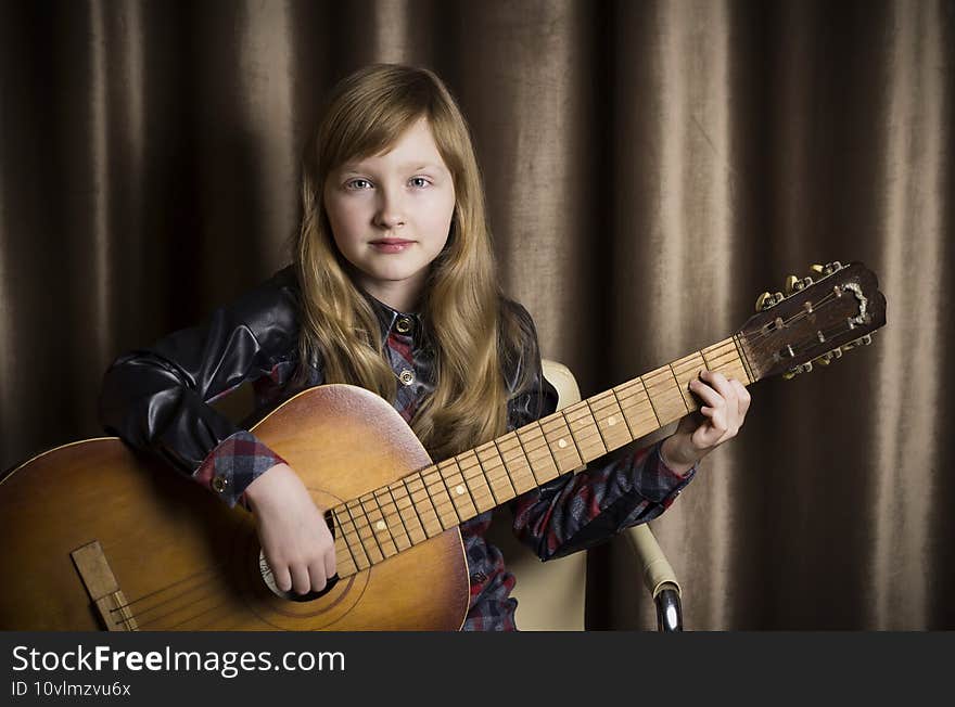 Little girl with a guitar on a brown background.