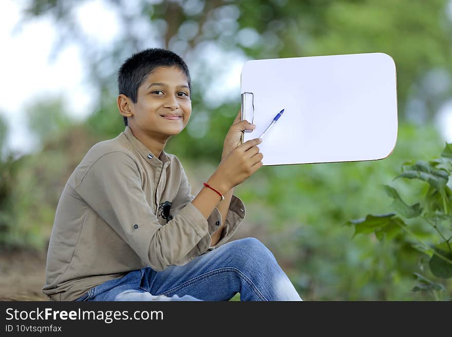 Cute little Indian/Asian boy showing writing pad pad with pen