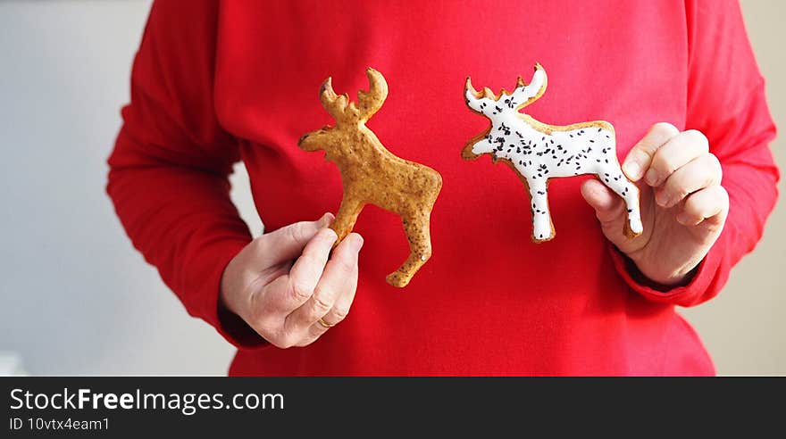 Older woman improvising with homemade cookies in the shape of a deer on a red jumper. Natural edible Christmas decor