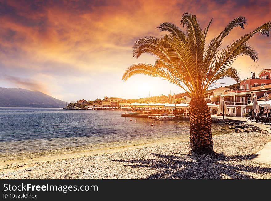 Fantastic Colorful Seascape over the Ionian sea. Palm tree on the beach under sunlight during sunset. Fickardo village. Kefalonia