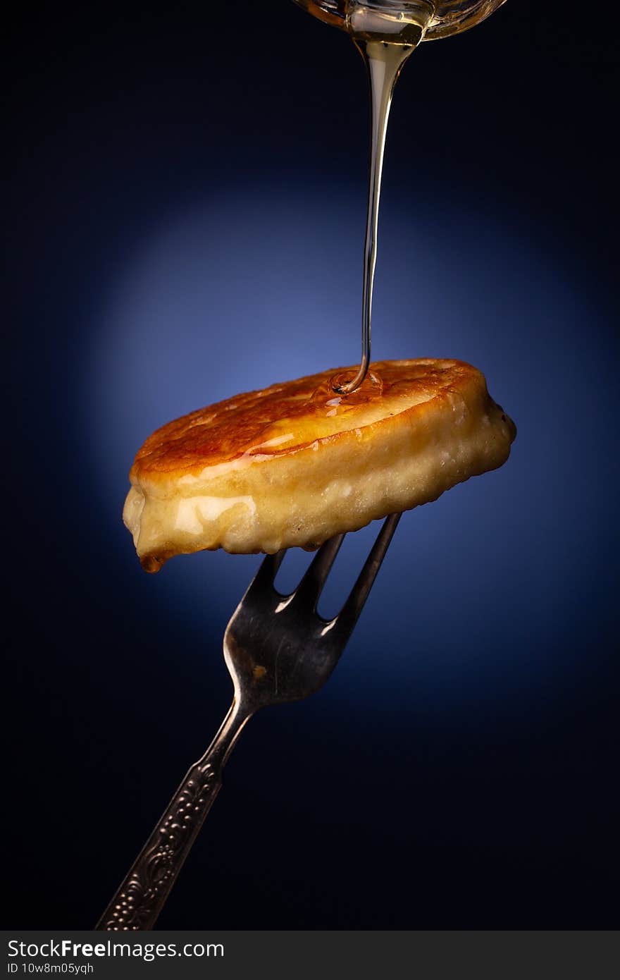 Fresh fried pancakes on a metal fork, dark blue background. Fresh fried pancakes on a metal fork, dark blue background