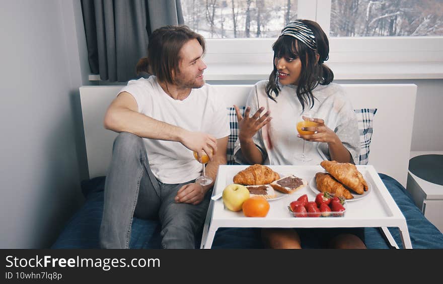 Young multiracial newlywed couple having breakfast in the bed on the honeymoon