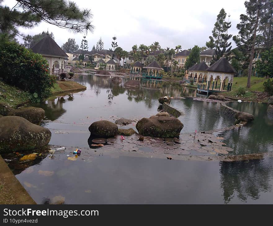 Little Lake And Stones Around, Cianjur, Indonesia - 2021. Tropical lake with buildings behind, beautiful and awesome for recreation place