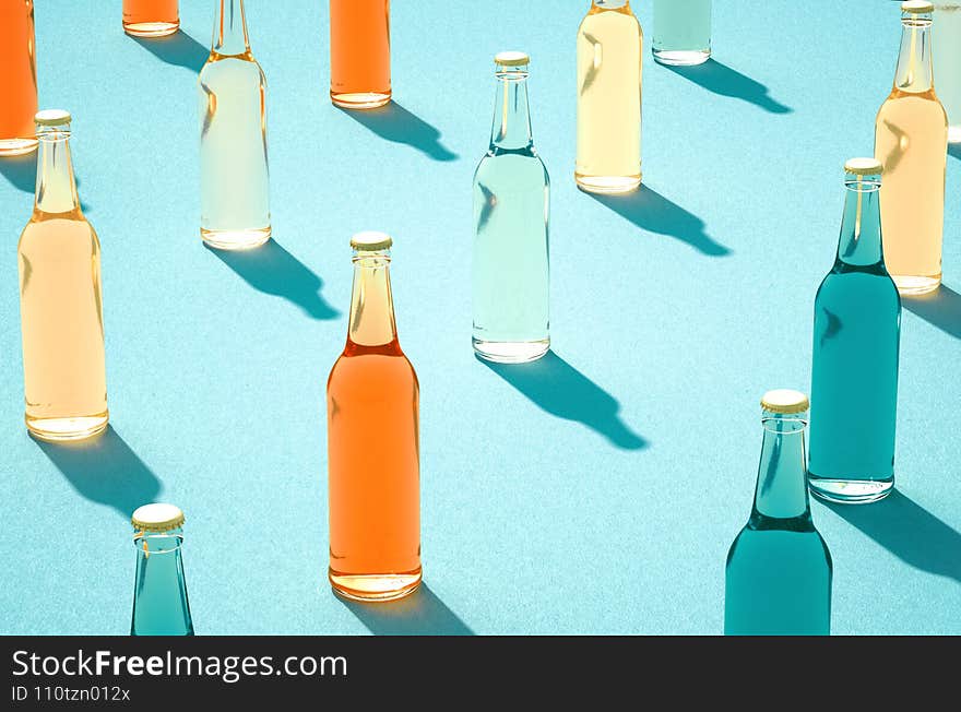 Various color glass bottles with shadows on blue surface