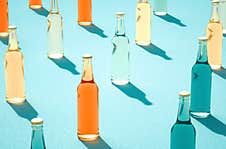 Various Color Glass Bottles With Shadows On Blue Surface Royalty Free Stock Images