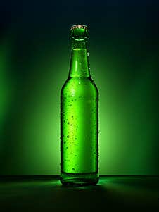 Single Green Beer Bottle With Water Drops Against Green Illuminated Background Royalty Free Stock Photography