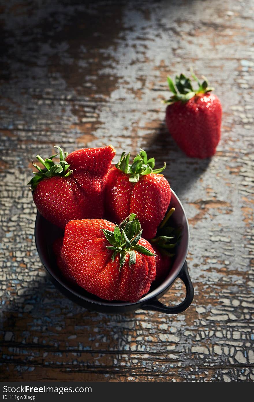 Portion of ugly ripe strawberries on a rustic table