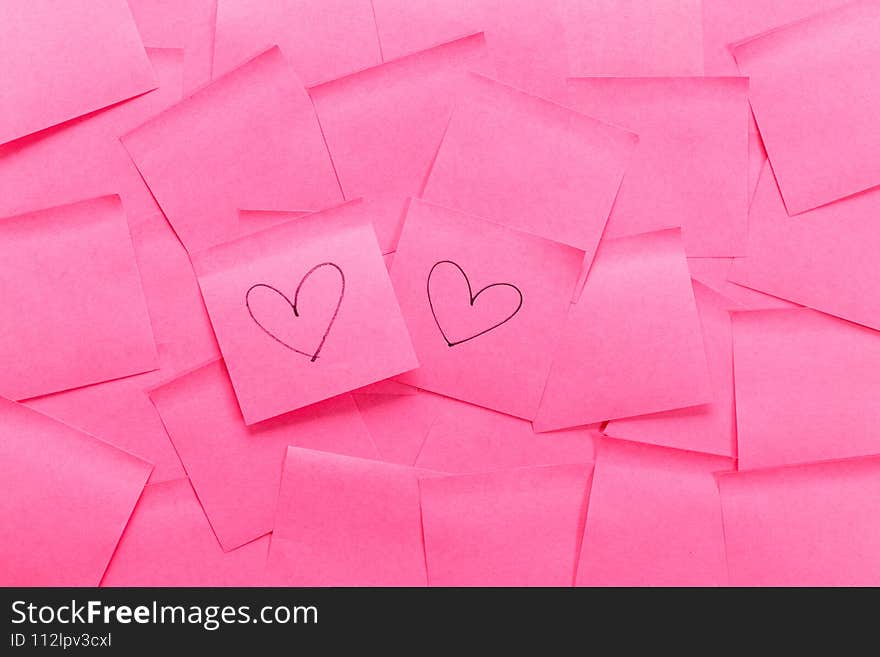 Pink sticky note with heart shaped handwriting on other pink sticky note background. Pink sticky note with heart shaped handwriting on other pink sticky note background