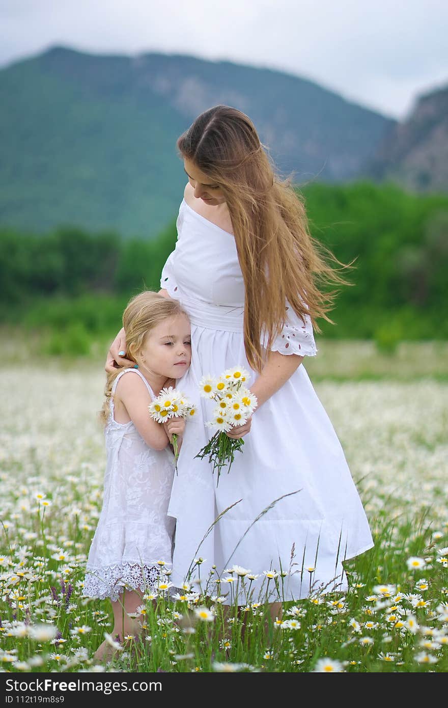 Happy mother and daughter in big camomile mountain meadow. Emotional, love and care scene. Happy mother and daughter in big camomile mountain meadow. Emotional, love and care scene