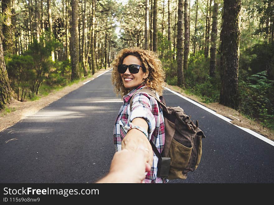 Happy travel couple women holding men hands with outdoor nature woods around - people following and enjoying vacation together - healthy lifestyle and backpack trip adventure in the forest. Happy travel couple women holding men hands with outdoor nature woods around - people following and enjoying vacation together - healthy lifestyle and backpack trip adventure in the forest