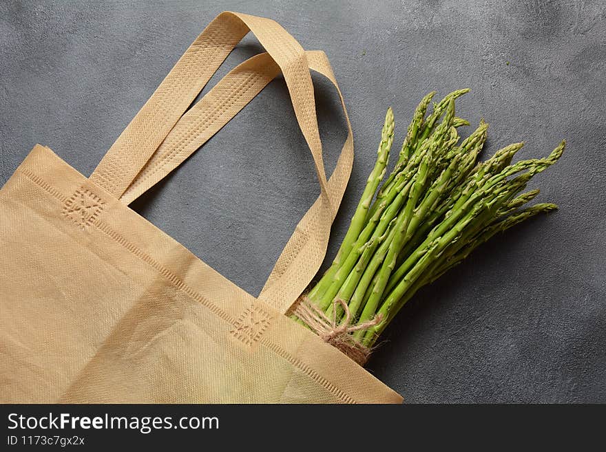 Reusable zero waste textile product bag filled with green asparagus and parsley
