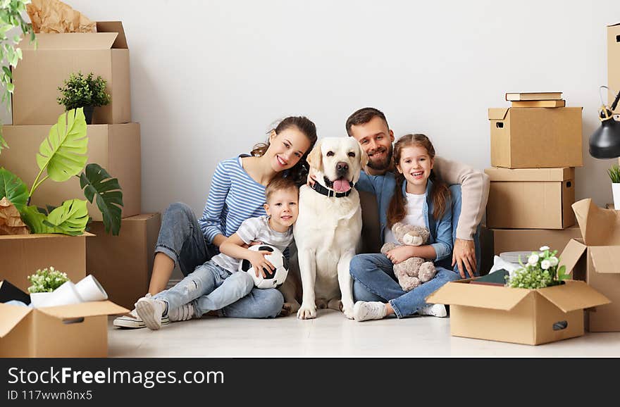 Delighted family: parents and cute kids and dog gathering on floor in living room with unpacked boxes in new flat and looking at camera. Delighted family: parents and cute kids and dog gathering on floor in living room with unpacked boxes in new flat and looking at camera