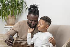 Father And Son, Dark Skinned African, Taking Selfie At Home Stock Photos